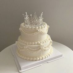 a three tiered wedding cake with a crown on top