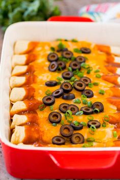 a red casserole dish filled with cheese and black olives