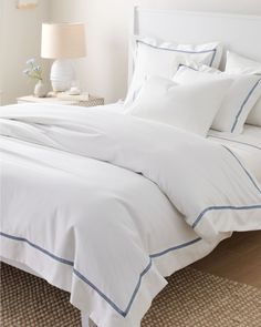 a bed with white sheets and blue trim