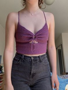 a woman wearing a purple crop top and jeans