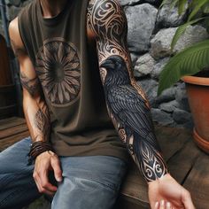 a man sitting on top of a wooden bench next to a potted plant and wearing a black bird tattoo