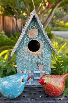 two colorful birds are sitting in front of a birdhouse