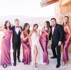 a group of people standing next to each other in formal wear posing for a photo