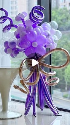 a vase filled with purple and white balloons