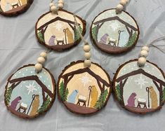 wooden ornaments with nativity scenes painted on them are hanging from a sheet of plastic