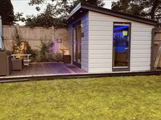 a small backyard shed is lit up with blue lights on the front and side doors