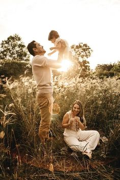 a man holding a baby while standing next to a woman and child in a field