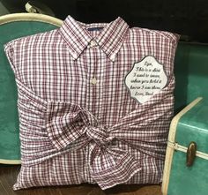 a plaid shirt with a bow on the front sits next to a green chair and suitcase