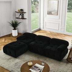 a living room with a large black couch in it's centerpiece and wooden coffee table