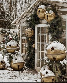 christmas decorations in front of a house with snow on the ground and trees around it