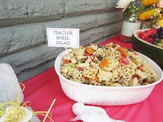 a bowl of pasta and vegetables on a table with a sign that says tractor wheel salad