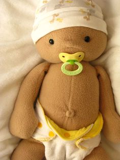 a teddy bear with a pacifier in its mouth laying on a white sheet and wearing a diaper