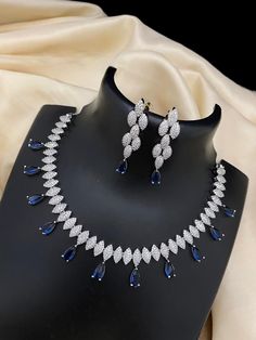 This exquisite necklace features a beautiful white gold plating with American diamond silver, a blue stone wedding choker, and CZ diamond Indian jewelry, creating an elegant Bollywood-inspired fashion statement. Each aspect of this necklace has been carefully crafted to ensure quality and style. Diamond Silver Necklace, Necklace Blue Stone, Diamond Choker Necklace, Silver Diamond Necklace, Stone Wedding, Diamond Choker, Kundan Necklaces, Cz Jewelry, White Necklace