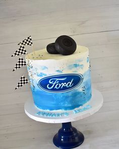 a blue and white cake with ford logo on the top is sitting on a pedestal