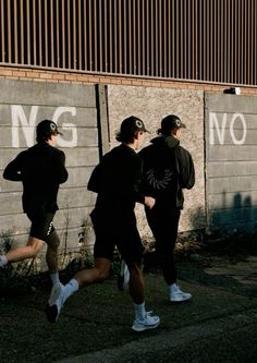 three men are running in front of a wall