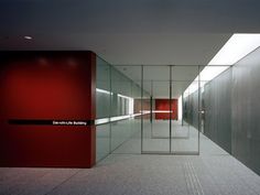 an empty hallway with glass walls and red doors