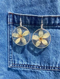 Beautiful handmade earrings made with real pressed white flowers set in epoxy resin. I shaped the wire frames by hand and collected these blooms in Maine. These earrings are perfect for celebrating nature's beauty. Wearing these earrings will allow you to carry a little piece of nature with you everywhere you go! 🌸STYLE: dangle drop earrings    🌸MATERIALS: real pressed white 5-petal flowers, epoxy resin, hypoallergenic nickel-free silver-colored ear wires, copper silver-colored wire frames 🌸SIZE: 2.5 inches long by 1.5 inch wide 🌸GIFT IDEAS: birthday, graduation, Valentine's Day, Christmas, Mother's Day, wedding - anyone who appreciates nature and has pierced ears would love these earrings as a gift! 🌸CARE: Store your earrings in a cool, dry, dark place, such as a jewelry box, out of Silver Flower Earrings With Pressed Flowers, Yellow Pressed Flower Earrings, Yellow Flower Earrings With Pressed Flowers, Yellow Flower-shaped Earrings With Pressed Flowers, Dry Pressed Flowers, White Flower Earrings, Epoxy Resin Jewelry, White Flower Earring, White Flower