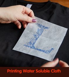 a woman's hand is stitching a t - shirt with blue thread