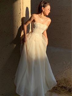 a woman in a white dress leaning against a wall with her back to the camera