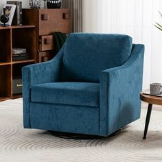 a blue chair sitting on top of a white rug next to a wooden coffee table