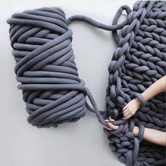 a woman is holding onto a large gray object that looks like a giant piece of rope