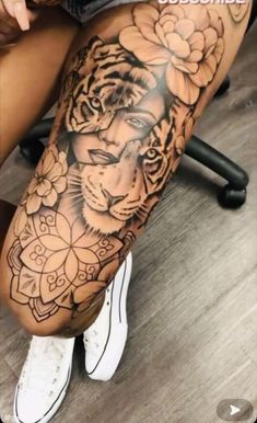 a woman's leg with a tiger and flowers tattoo on it, sitting in front of a chair