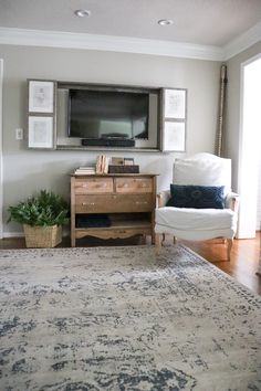 a living room with a rug, chair and television on the wall above it's flat screen tv