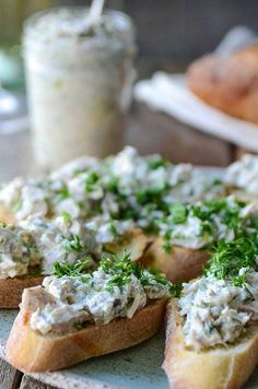 a plate topped with bread covered in blue cheese and dill relish next to a jar of yogurt