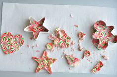 several decorated cookies sitting on top of a white table next to candy canes and sprinkles