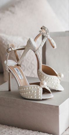 a pair of white high heeled shoes with pearls