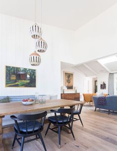 a dining room table with four chairs and a bowl of fruit on the table in front of it