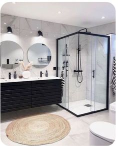 a modern bathroom with black and white fixtures, marble counter tops, and round mirrors