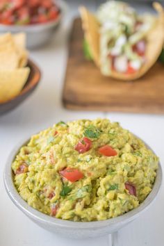 guacamole in a bowl with tortilla chips and salsa on the side