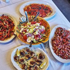 a table topped with plates of food next to bowls of salads and other foods