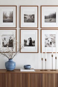 a blue vase sitting on top of a wooden table next to pictures and candles in front of them