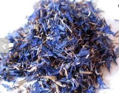 a pile of dried blue flower petals on a white surface