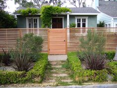 a fenced in front of a house with lots of plants