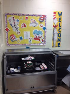 a metal cabinet filled with lots of cards in front of a welcome sign and bulletin board