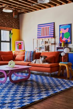 a living room filled with colorful furniture and art on the walls, along with a large rug