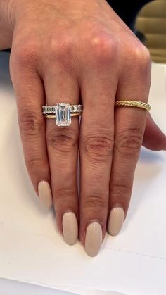 a woman's hand with two rings on top of it and a ring in the middle