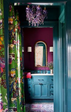 a bathroom with purple walls and green curtains on the window sill, blue vanity and mirror