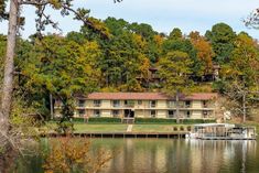 an apartment building on the edge of a body of water with trees in the background