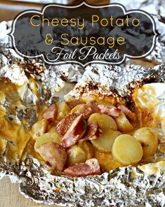 a foil pan filled with potato and sausage casserole on top of a wooden table