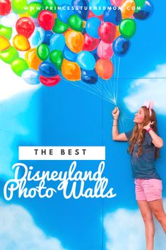 a woman holding balloons in front of a blue wall with the words, the best disneyland photo walls