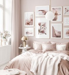 a bedroom with pink walls and pictures on the wall above the bed in front of it