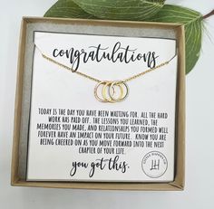 two interlocked rings necklace in a box with congratulations written on the front and back