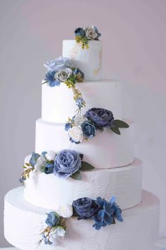 a three tiered white cake with blue flowers on top