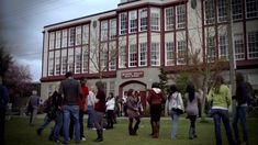 a group of people standing in front of a large building with many windows and doors