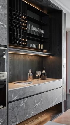 a modern kitchen with marble counter tops and black cabinetry, along with wine glasses