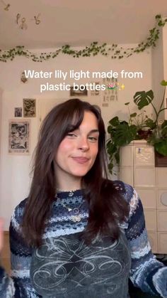 a woman with long dark hair wearing a sweater in front of a plant and text that reads water lily made from plastic bottles